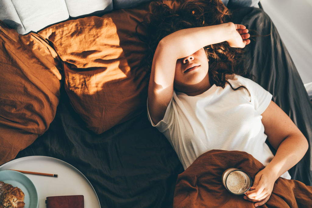 Femme allongée sur son lit, visiblement préoccupée