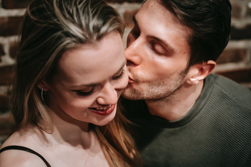 Homme embrassant la joue d'une femme souriante