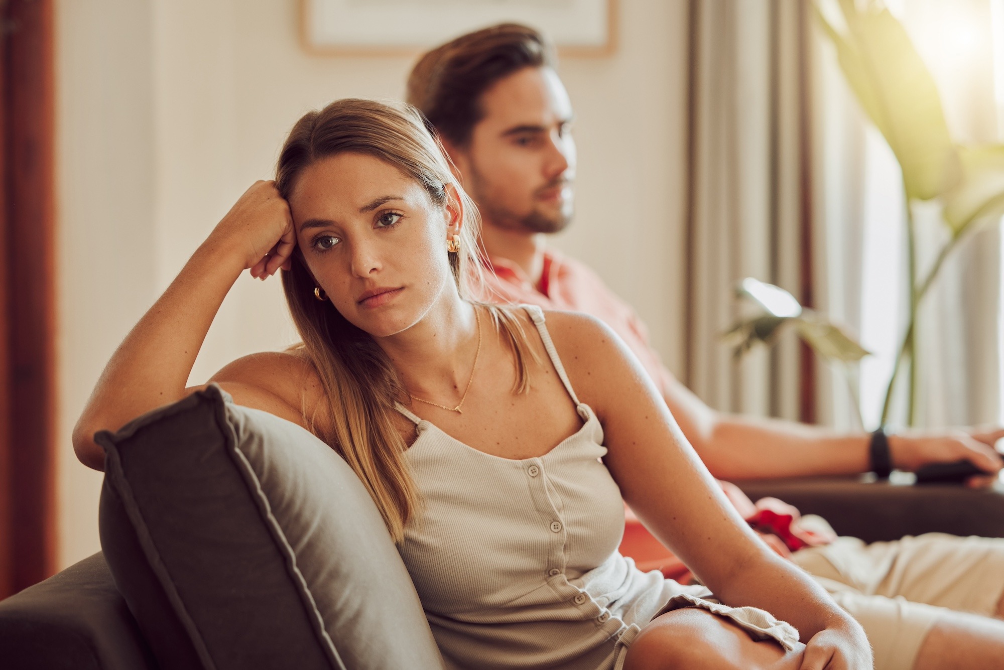 Couple assis dos à dos dans un lit, illustrant l'éloignement