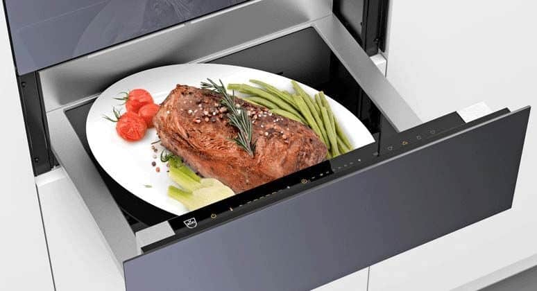 Personne utilisant le tiroir chauffant d'une cuisinière