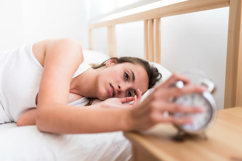 Personne tenant une tasse de thé, contemplative, à la fenêtre de nuit