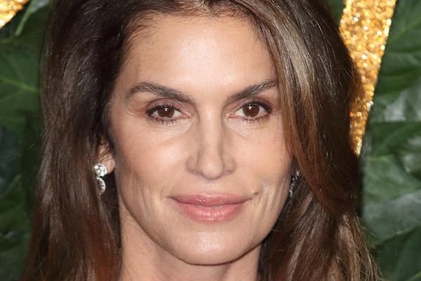Cindy Crawford souriante, arborant des cheveux argentés avec naturel et confiance