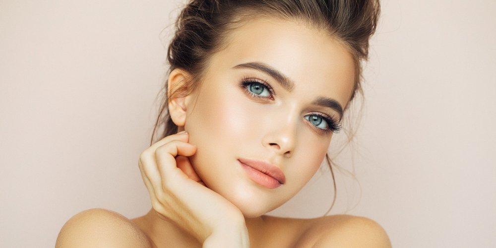 Femme appliquant un soin sur son visage, peau nette et lumineuse