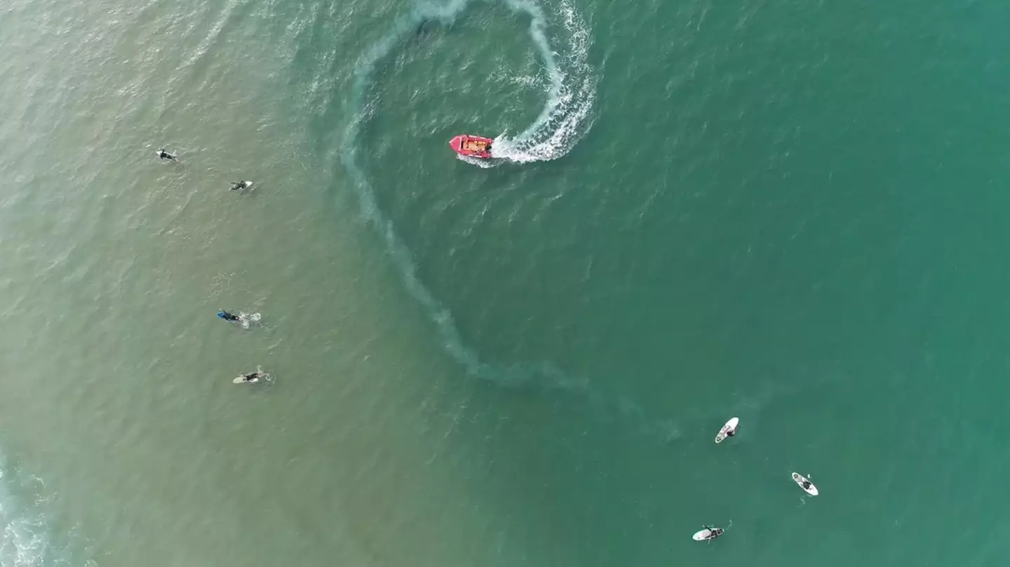 Vue aérienne d'une plage avec un bateau et des surfeurs