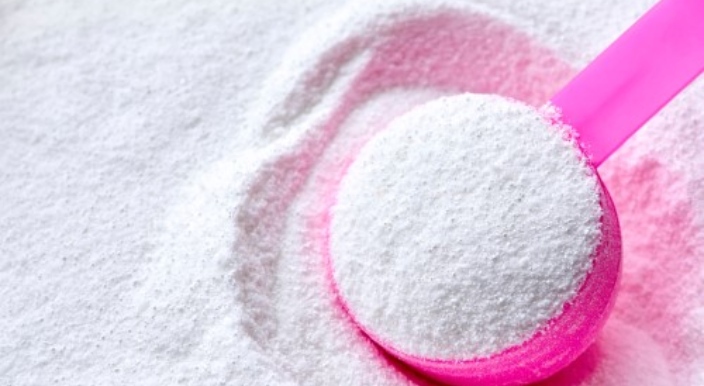 Cuillère doseuse contenant de la lessive en poudre